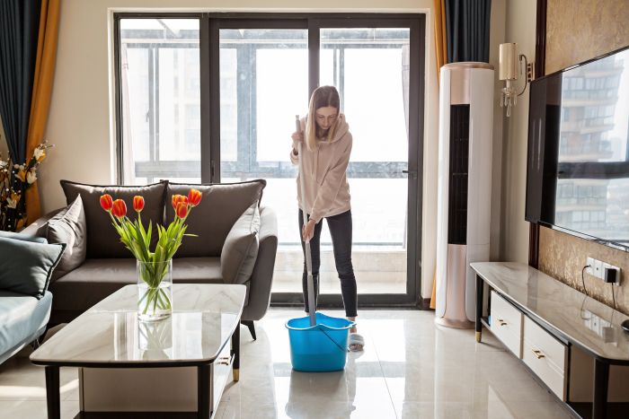 Frau Beim Putzen Mit Wischmopp Und Eimer Im Wohnzimmer, Tulpen Auf Dem Tisch.