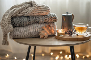 Home Autumn Composition With Tea Knitted Sweaters Interior Room Blurred Background With Garland
