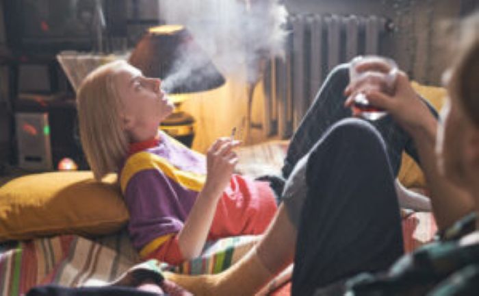 Young Woman Lying Bed Smoking Cigarette With Her Boyfriend Sitting Bed Drinking Wine 300X185 1