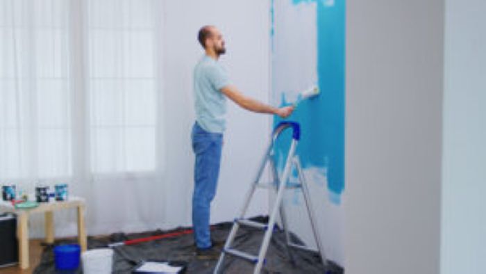 Handyman Painting Wall With Roller Brush Dipped White Paint Handyman Renovating Apartment Redecoration Home Construction While Renovating Improving Repair Decorating 300X169 1