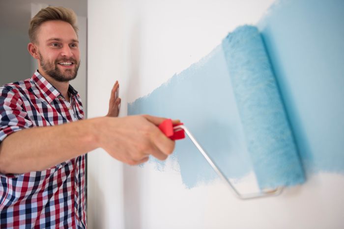 Young Man Painting Blue Wall