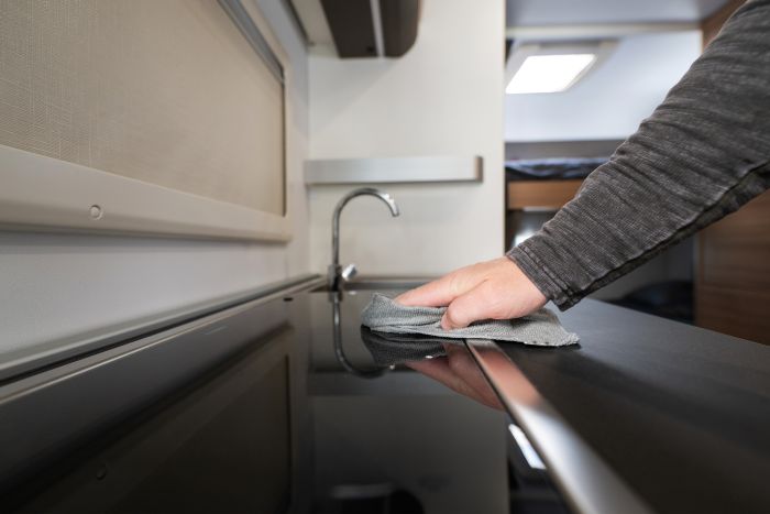 Men Cleaning Motorhome Camper Van Kitchen Area With Soft Cloth