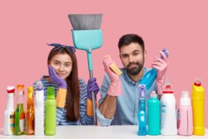 Ein Mann und eine Frau halten Reinigungsmittel in den Händen und lächeln freundlich.