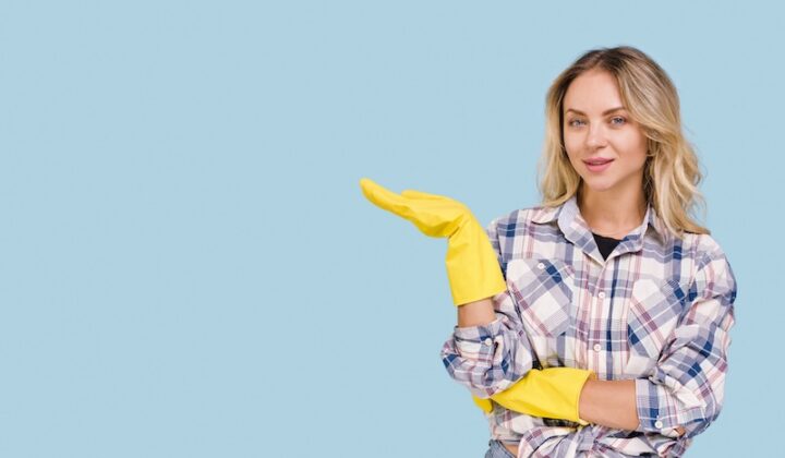 Eine Frau mit gelben Handschuhen hält einen Reinigungshandschuh in der Hand.