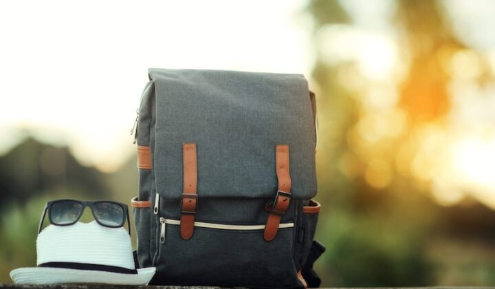 Ein Rucksack, eine Sonnenbrille und ein Hut liegen auf einer Mauer.