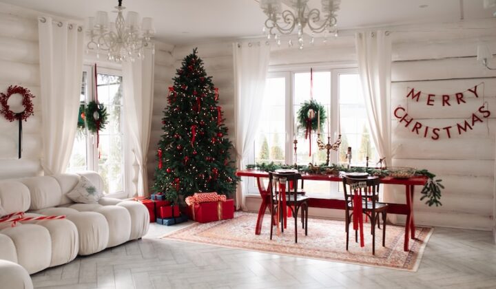 Wohnzimmer zur Weihnachtszeit, geschmückt mit einem prächtigen Baum und festlichen Ornamenten.
