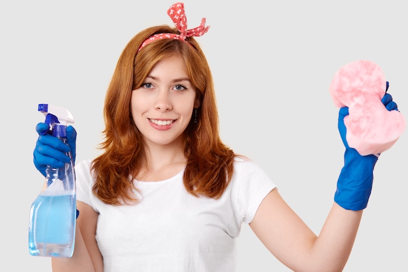 Isolated Shot Satisfied Female Janitor Holds Spray Sponge Wears Headband White T Shirt Protective Rubber Gloves Ready Cleaning Stands Indoor Housekeeping Hygiene Concept