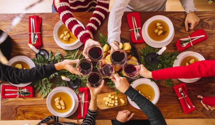 Menschen feiern Weihnachten, indem sie an einem festlich gedeckten Tisch anstoßen.
