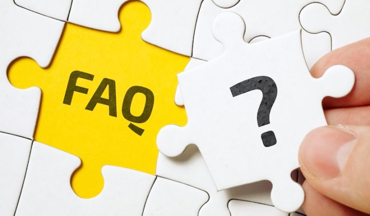 A hand holds a white puzzle piece with a question mark, above a yellow space labeled "FAQ." The image suggests solving questions or uncertainties.