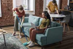 people sitting in a living room with one of them cleaning the floor