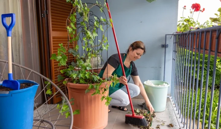 housewife sweeping dry leaves balcony garden spring cleaning