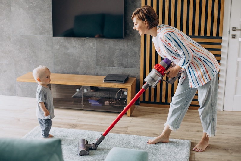 Young Mother With Toddler Son Cleaning Up Home