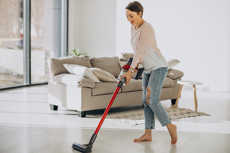 Young Woman With Rechargeable Vacuum Cleaner Cleaning Home