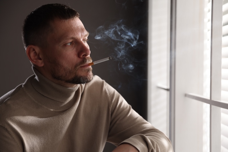 Man Smoking Cigarette Near Window Room
