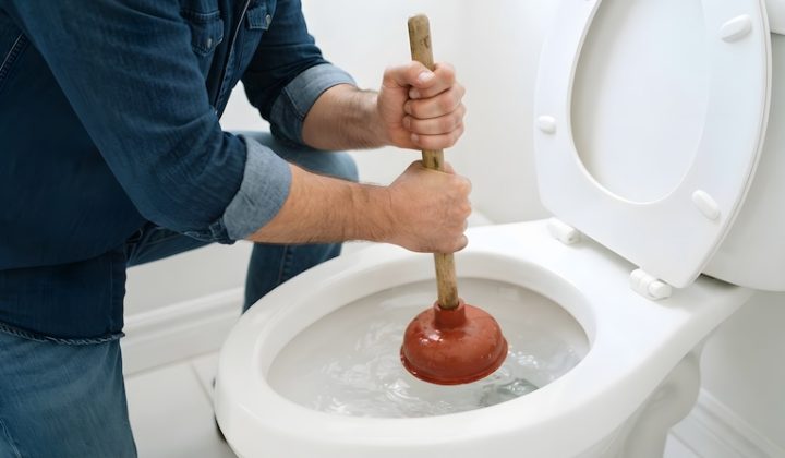 man using plunger unclog toilet bathroom close up