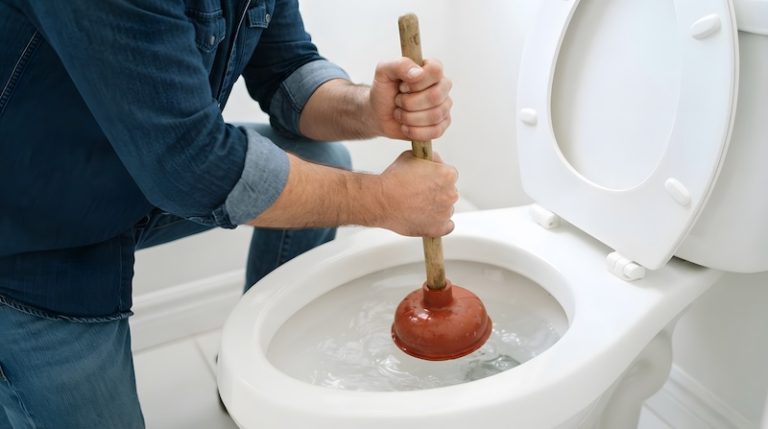 man using plunger unclog toilet bathroom close up