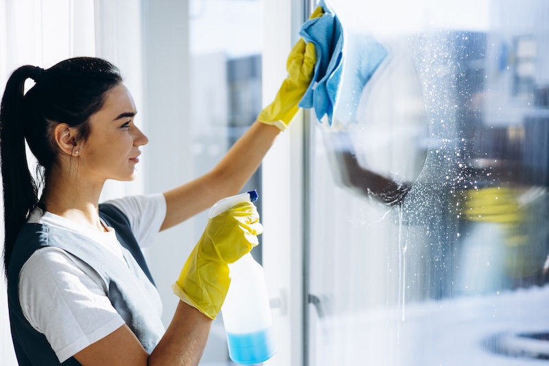 Female Housekeeper Wearing Yellow Gloves Washing Windows