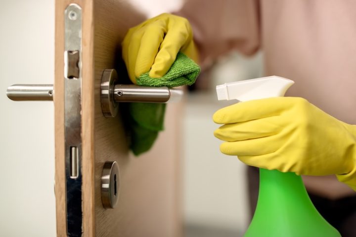 closeup woman disinfecting door handle home
