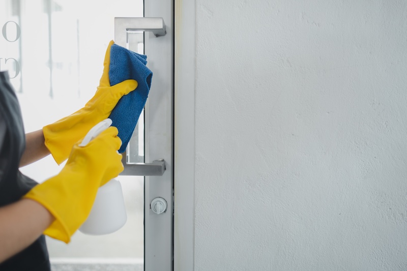 Housekeeper Cleaning Furniture Home Wear Apron Rubber Gloves Protect Against Cleaning Chemicals Female Wiping Down Door Handle With Cleaning Spray Cleaning Idea