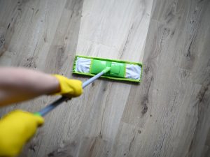 male hand with yellow protective gloves hold green plastic mop
