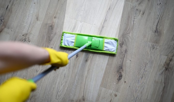 male hand with yellow protective gloves hold green plastic mop